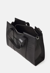 Sac à main en cuir noir texturé avec double poignée et fermeture éclair partiellement ouverte sur le dessus sur un fond uni.