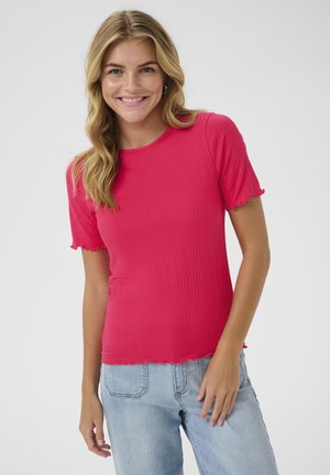 Haut côtelé à manches courtes de couleur rose vif, avec un col rond et des bords festonnés, accompagné d'un jean bleu clair à coupe décontractée.