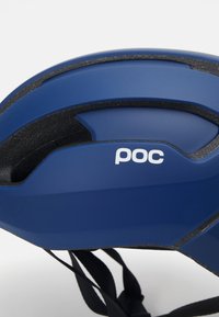 Casco da ciclismo blu con finitura lucida, dettagli neri, fessure di ventilazione e un logo "poc" bianco ben visibile sul lato.