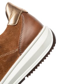 Brown suede sneaker featuring a metallic bronze accent, a textured leather overlay, and a white midsole with a jagged brown outsole.