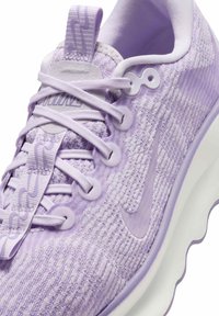 Chaussure de sport violette avec une tige texturée, des accents lisses contrastants et une semelle flexible au design ondulé ; comprend un système de laçage.
