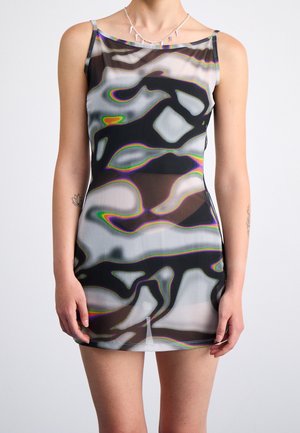 Vrouw draagt een nauwsluitende, meerkleurige, abstracte, mouwloze mini-jurk met dunne bandjes en een zilveren ketting met spikes.