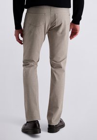 Hellgraue, strukturierte Stoffhose mit schlanker Passform, zwei Gesäßtaschen und einem dezenten Muster. Die Schuhe sind dunkelbraun mit glänzender Oberfläche.