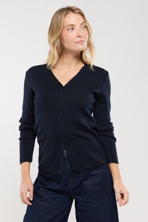 Granatowy sweter z dzianiny, z dekoltem w serek, długimi rękawami, z zapięciem na guziki oraz dwiema przednimi kieszeniami. Tkanina wydaje się miękka o gładkiej strukturze.