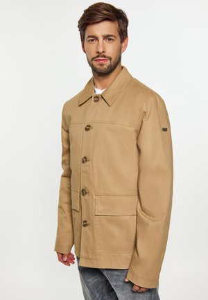 Beige, lichte jas met knoopsluiting aan de voorkant, kraag, twee grote voorzakken en subtiele stiksels. Gladde textuur, casual ontwerp.