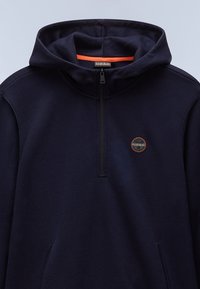 Felpa con cappuccio blu navy in tessuto morbido e testurizzato, con zip parziale frontale, foderata internamente in arancione e un piccolo logo ricamato sul petto.