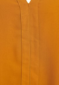 Orange Stoff mit glatter Textur, ausgestattet mit einem V-Ausschnitt und zwei vertikalen Nähten in der Mitte. Einfaches und minimalistisches Design.