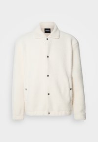 Hvid fleecejakke med krave, forsynet med sorte trykknapper og sidelommer. Blød tekstur og løstsiddende design.