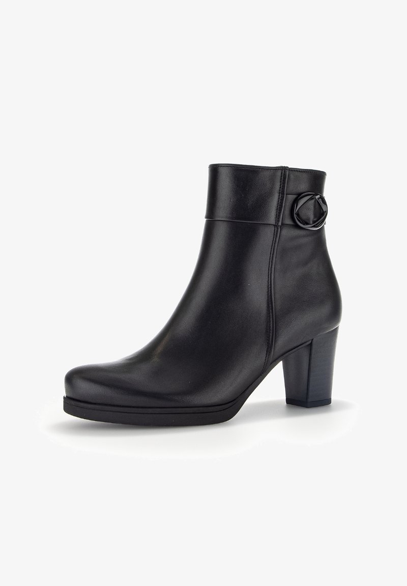 Bottine noire en cuir avec bout rond, talon bloc, dessus plié et boucle circulaire décorative sur le côté extérieur.