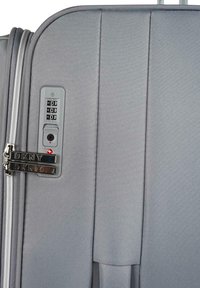 Maleta gris de DKNY con superficie texturizada, doble cremallera, candado de combinación integrado y elegantes acentos de hardware.