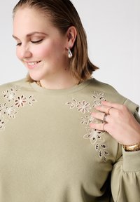 Olijfgroene sweatshirt met bloemrijke borduurwerk in lichtroze en beige, ronde halslijn en opgepofte mouwen.