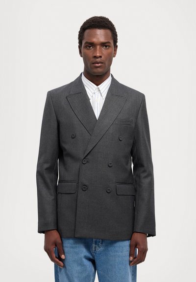 Mørkegrå dobbeltbrystet blazer med notch-kraver, to forlommer og en glat tekstur, parret med en lys stribet skjorte.