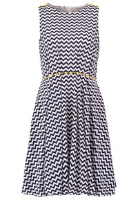 Robe sans manches à motifs zigzag navy et blanc, avec un corsage ajusté, une taille marquée et un accent jaune au niveau de la taille.