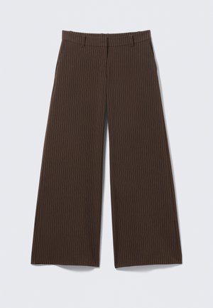 Pantaloni larghi a righe marroni con passanti per cintura, zip anteriore e tasche laterali, distesi su uno sfondo chiaro.