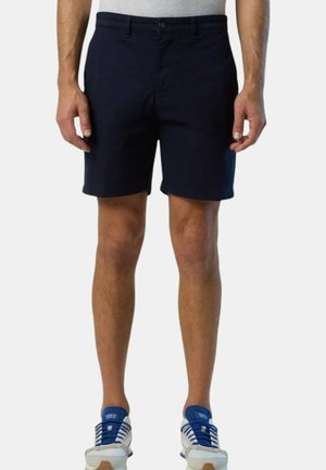 Pantaloni corti blu navy in materiale misto cotone, con frontale piatto, passanti per la cintura e tasche laterali. Indossati con scarpe casual.