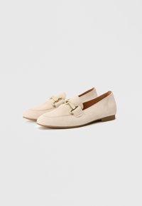 Beige suede loafers featuring a gold-tone hardware accent and a low heel. The design includes side stitching and a rounded toe.