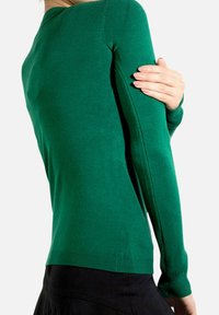 Pull vert à manches longues en tissu doux, avec un design ajusté, des poignets côtelés et une texture lisse avec des coutures propres.