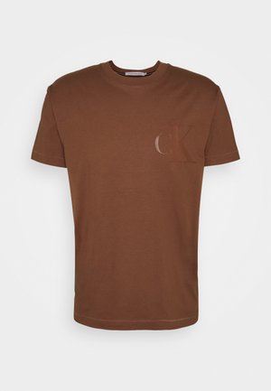 Brązowy t-shirt z krótkim rękawem i okrągłym dekoltem, z subtelnym, błyszczącym logo "cK" po lewej stronie na piersi i gładkim wzorem.