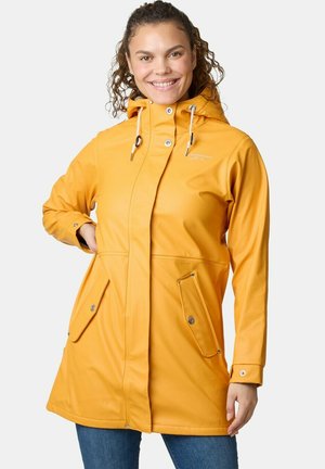 Woman wearing a yellow hooded raincoat with snap-button pockets and cuffs, smiling, with one hand on her hip against a white background.