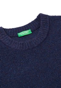 Navyblauer Pullover aus einem weichen, strukturierten Stoff mit geripptem Rundhalsausschnitt. Mit einem grünen Etikett, auf dem "United Colors of Benetton" steht.