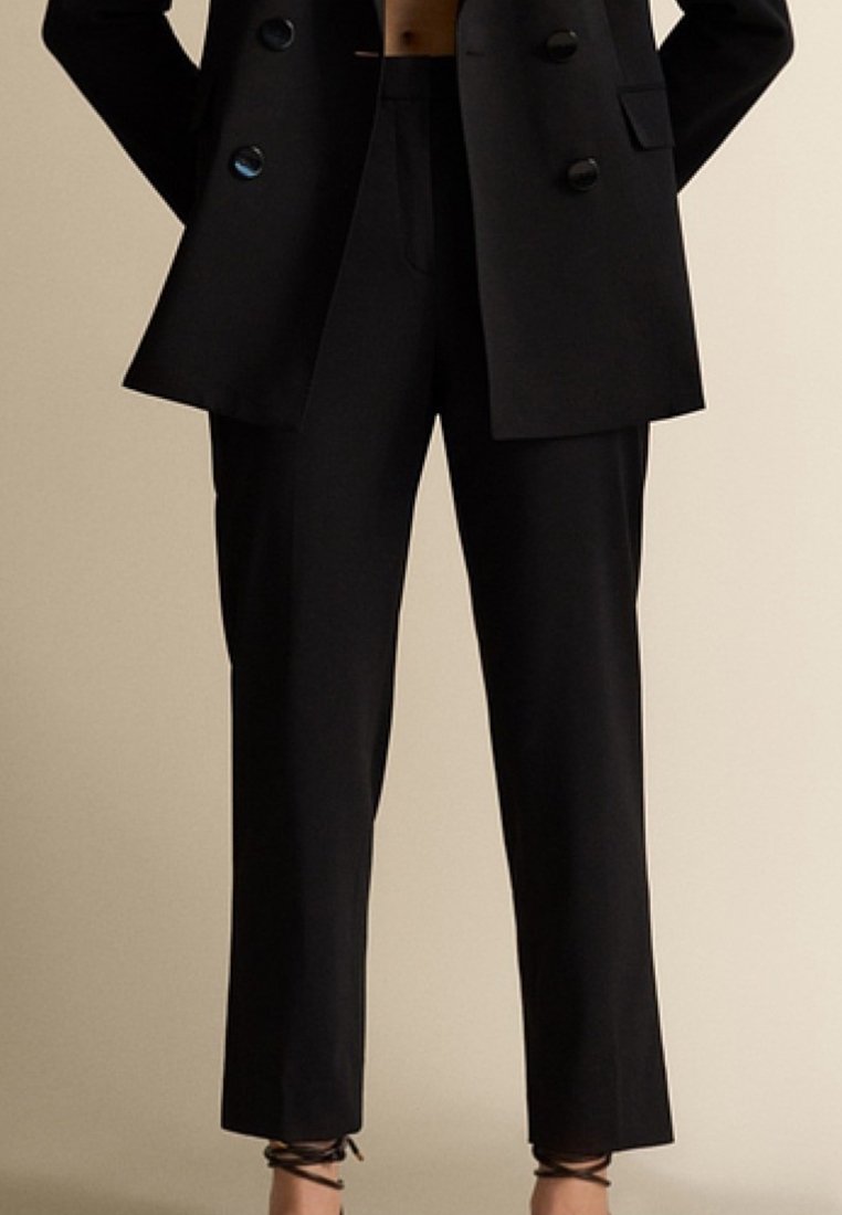 Schwarze, taillierte Hose mit geradem Schnitt, ausgestattet mit dezenten Vorderfalten und einem mittelhohen Bund. Hergestellt aus glattem Stoff mit einer eleganten Oberfläche.