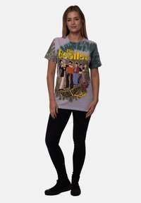 Tie-dye t-shirt in light purple and green featuring The Beatles graphic. Short sleeves, round neck, and relaxed fit. Paired with black pants.
