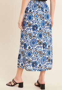 Maxi gonna con motivo floreale blu e nera, con vita arricciata e un design fluido. Abbinata a sandali neri con tacco.