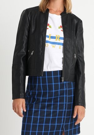 Černá kožená motorkářská bunda s přiléhavým střihem, na zip vpředu a s bočními kapsami. Natažena přes bílé tričko s potiskem a modrou károvanou sukní.