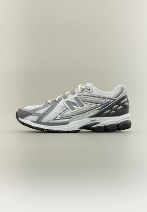 Biało-szary but do biegania New Balance z siateczkową cholewką, wyściełaną podeszwą i czarną gumową podeszwą zewnętrzną, pokazany z boku na neutralnym tle.