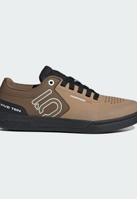 Vaaleanruskeat maastopyöräilykengät, joissa on mustat yksityiskohdat, rei'itetty päällinen ja kumipohja, jossa on teksturoitu pito. Brändin logo näkyy selvästi.