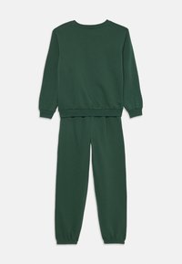 Zeleni pulover in usklajene trenirke iz mehkega materiala. Komplet vsebuje krojni ovratnik, dolge rokave ter elastične manšete in pas.