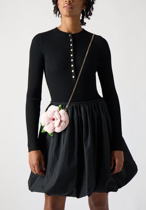 Vestito nero a maniche lunghe con coste e bottoni dorati, abbinato a una borsa a tracolla floreale rosa con dettagli verdi e una catena.