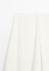 Een gladde, gevouwen witte stof hangt elegant, waarbij de textuur tegen een effen witte achtergrond wordtgetoond.