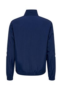 Marineblauwe lichte jas met lange mouwen, opstaande kraag, elastische manchetten en elastische tailleband, gezien van achteren.