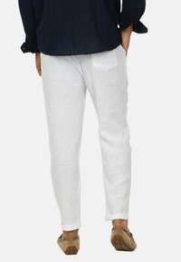 Pantaloni bianchi in lino con una vestibilità rilassata, texture sottile e orli arrotolati. Presentano una tasca posteriore con un dettaglio a contrasto.
