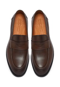 Par de mocasines de cuero marrón con detalle de correa cosida y plantillas de cuero color canela con el nombre de la marca grabado, mostrados desde una vista superior.