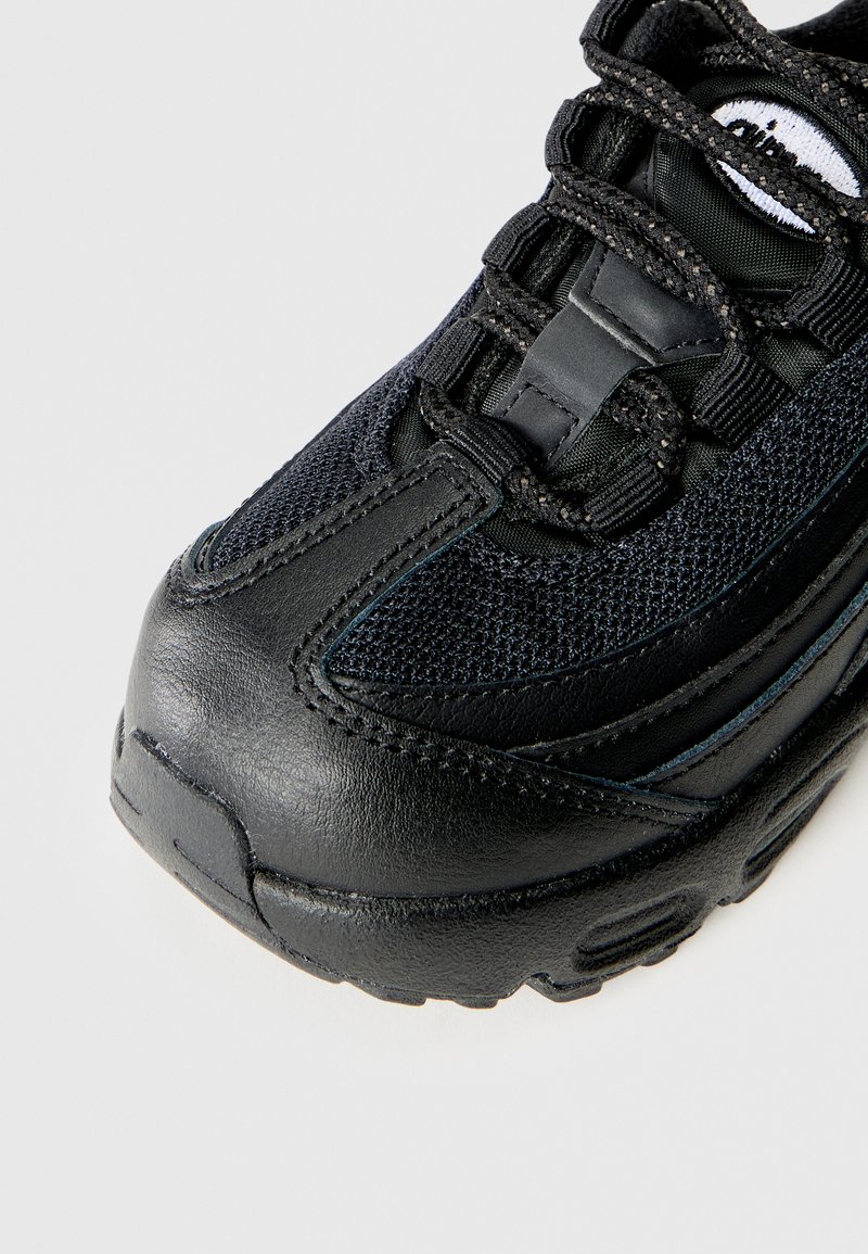Sneakers noirs avec des panneaux en mesh et en cuir, des coutures détaillées et des lacets à motifs sur fond blanc.