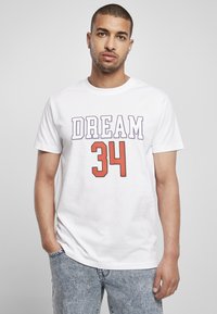 Bílý bavlněný tričko s potiskem "DREAM" v purpurové barvě a "34" v oranžové, krátké rukávy, kulatý výstřih a volný střih. Nosené s světle modrými džíny.