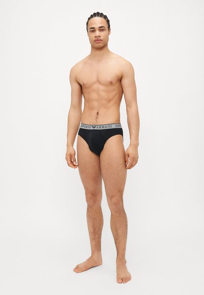 Černé slipy s šedým pasem, na kterém je text "Emporio Armani". Hladká tkanina, dobře padnoucí střih a minimalisticý styl.
