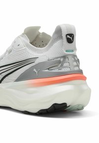 Zapatilla de running blanca con parte superior de punto texturizado, detalles en gris, entresuela rosa y suela de goma negra con un logo en el talón.