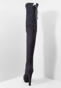 Stivali sopra il ginocchio realizzati in un tessuto navy scuro, con punta affusolata, alto tacco a stiletto e parte superiore arricciata con dettaglio del cordoncino.