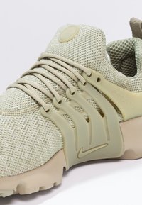 Světlounce zelený síťovaný teniska s plastovým překryvem, kulatou špičkou, elastickými tkaničkami a béžovou gumovou podrážkou, s minimalistickým logem.