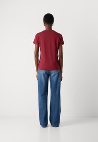 Burgundy T-shirt with a crew neckline, paired with wide-leg blue jeans. Soft cotton fabric with a smooth texture, plain design, no patterns.