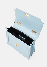 Ljusblå läderhandväska med scallopad öppning, guld detaljer, svart foder och en strukturerad rektangulär form.