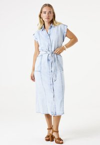 Helles blaues Jeanskleid mit durchgehender Knopfleiste, kurzen aufgerollten Ärmeln und tailliertem Bund. Es verfügt über zwei seitliche Taschen und einen geraden Schnitt.