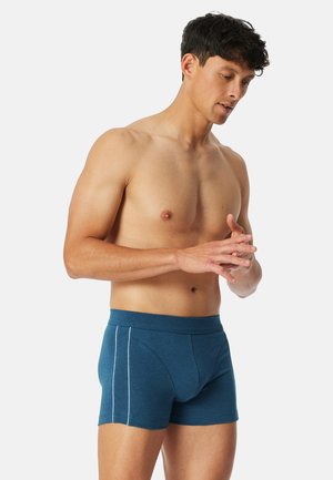 Blaue Boxershorts aus weichem Stoff, mit enganliegendem Schnitt, kontrastierenden weißen Seitennähten und einem elastischen Bund.