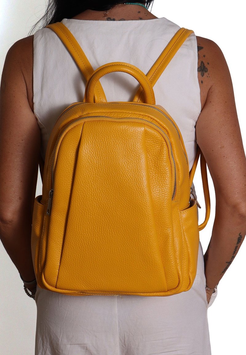 Zaino in pelle gialla, finitura strutturata, scomparti con zip, manico arrotondati, spallacci regolabili, design elegante.