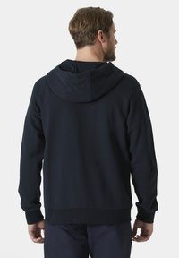 Sudadera con capucha de color azul marino, con un bolsillo canguro en la parte delantera, una capucha amplia, y puños y cintura acanalados, hecha de un tejido suave con una textura lisa.