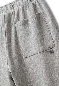 Graue Jogginghose aus einem Baumwollmischgewebe, mit einem elastischen Bund, einer aufgesetzten Tasche auf der Rückseite und einem kleinen dekorativen Etikett.