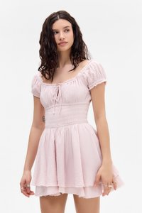 Vestido corto de color rosa claro con mangas abullonadas, corsé fruncido y falda en capas. Tela texturizada con diseño recogido y detalles de dobladillo sin terminar.
